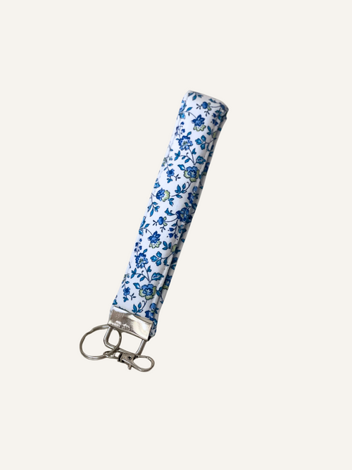 a padded keyring wristlet in ditsy blue floral on white fabric on a warm cream background