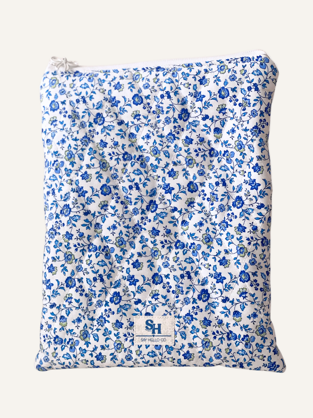 a quilted book sleeve in ditsy blue floral on white fabric on a warm cream background