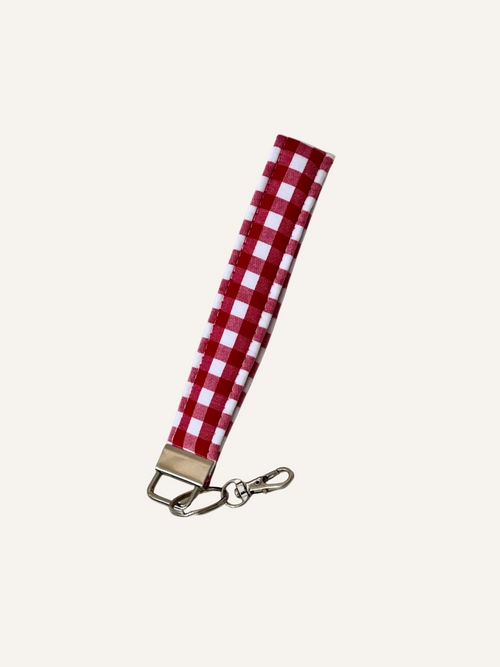Red and white checkered padded fabric keychain wristlet on a warm cream background