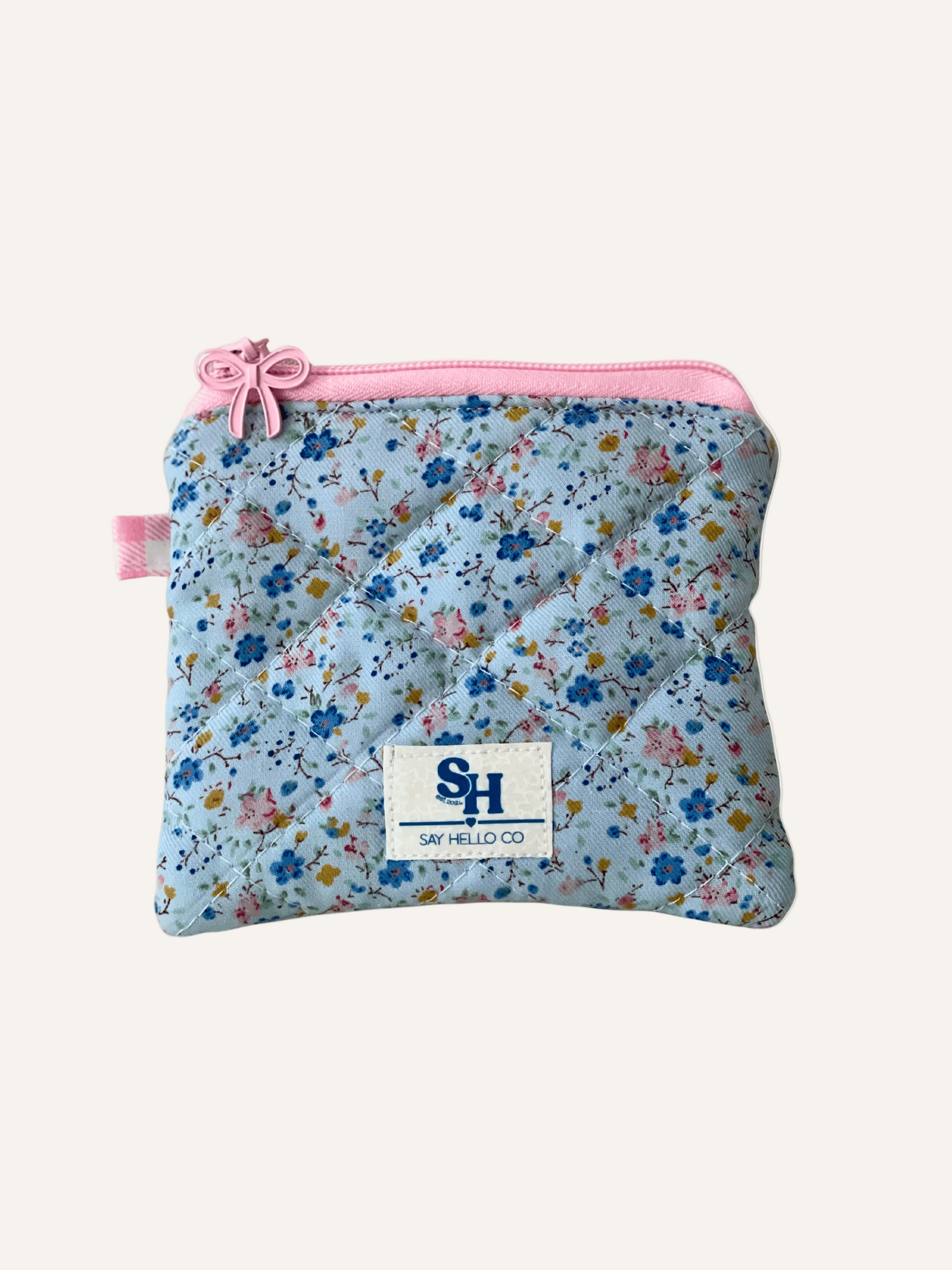 Blue and pink floral-patterned pouch with pink zipper on a warm cream background