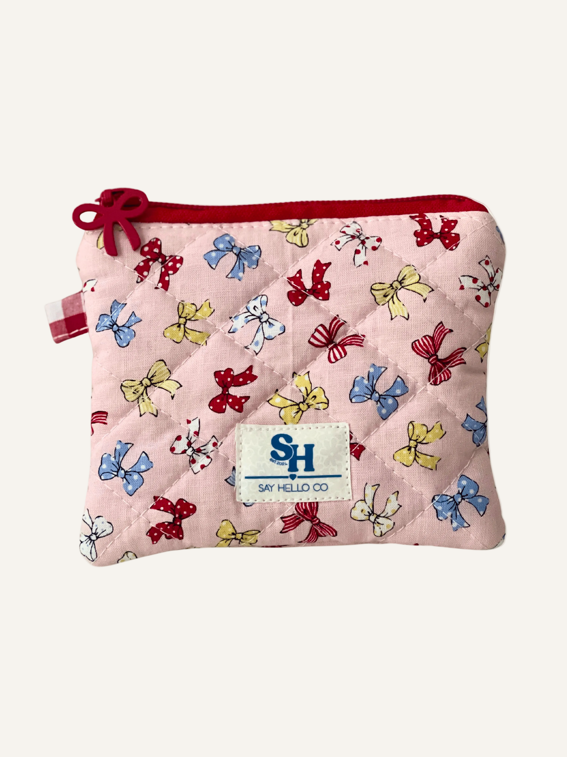 A depression era inspired pink bow print with tiny colourful bows, red bow zipper on a zippered mini pouch