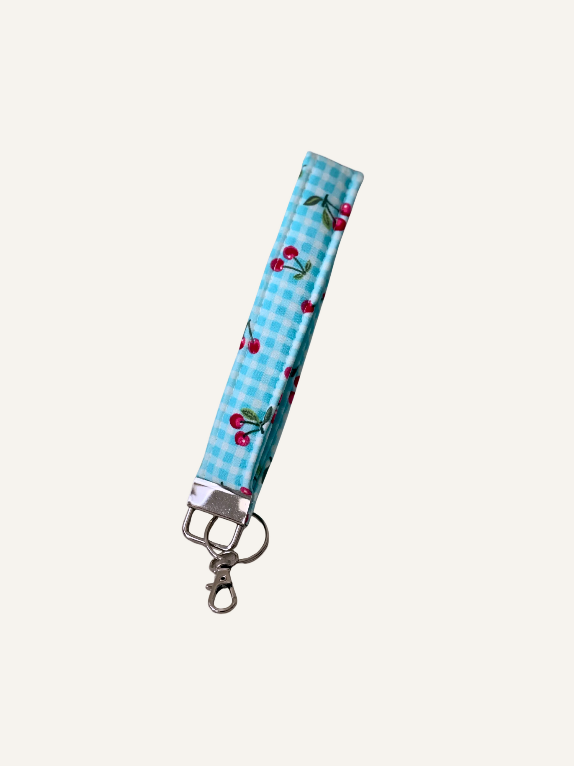 padded fabric keyring wristlet in blue gingham with pink cherries on a warm cream background