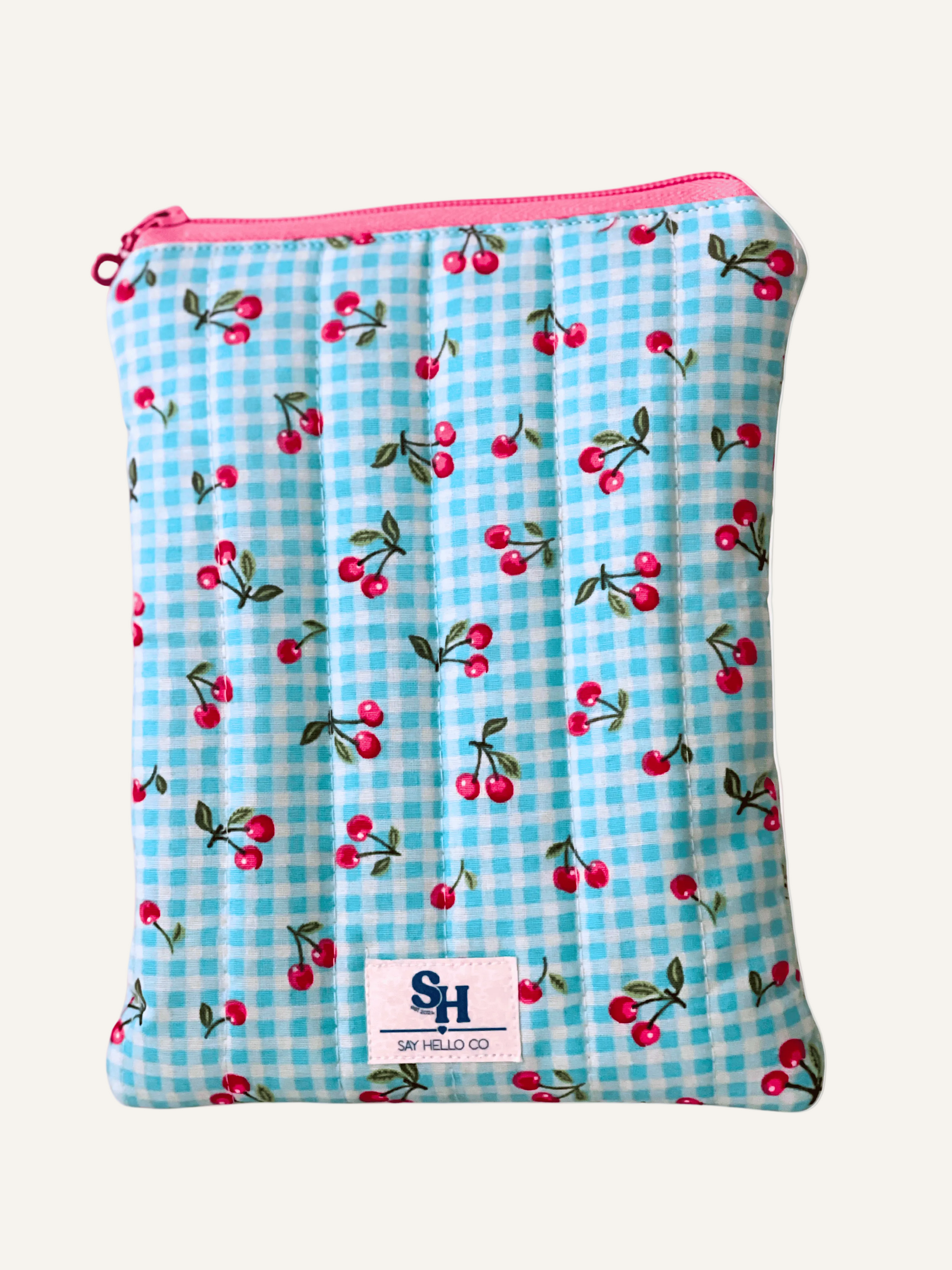 Quilted Fabric book sleeve with blue gingham and pink cherry pattern on a warm cream background