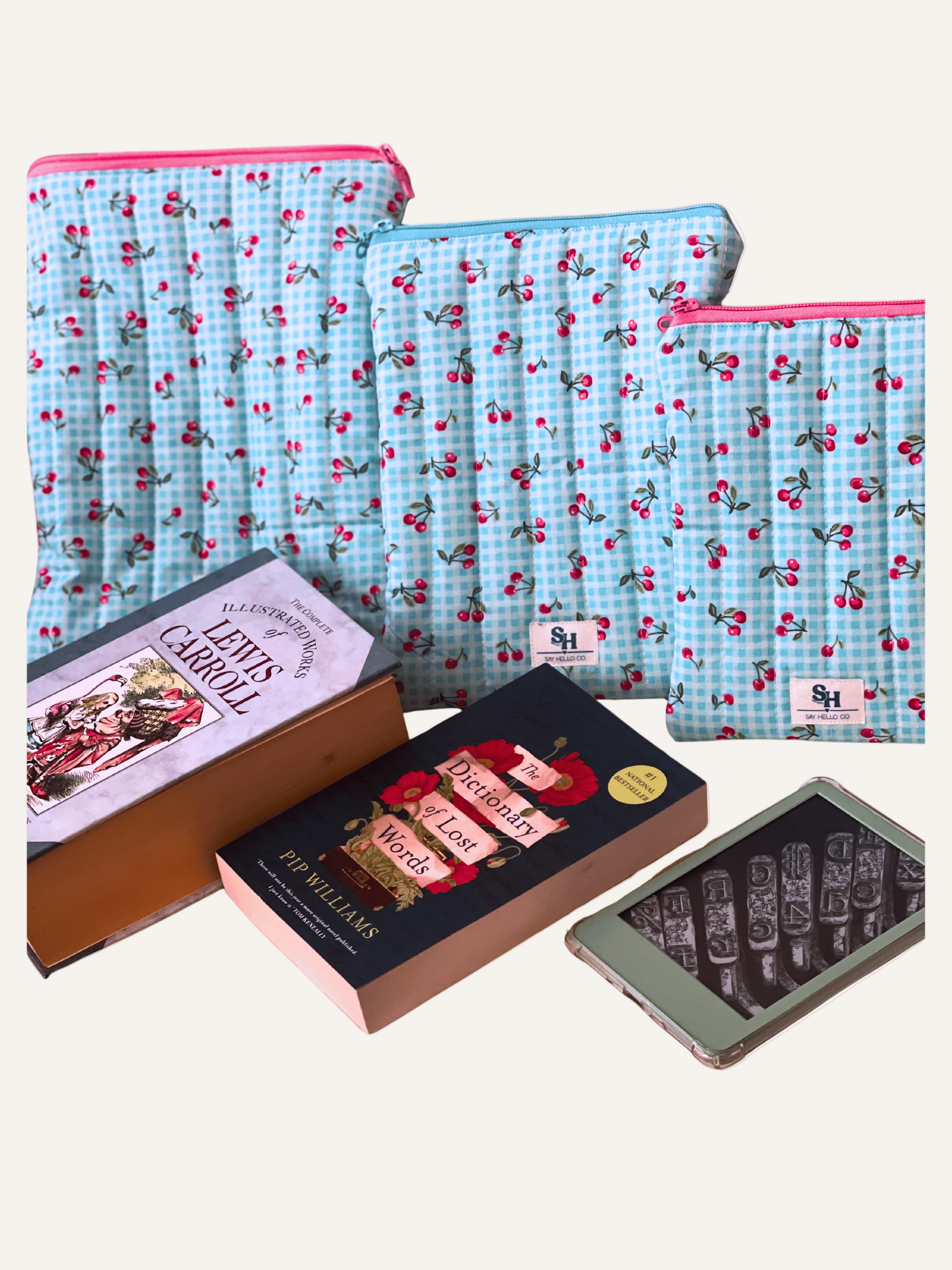 Set of fabric bags with a gingham blue and pink cherry pattern and books on a warm cream background