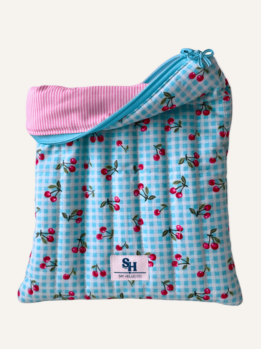 quilted booksleeve with cherry pattern and pink and white pinstripe lining on a warm cream background