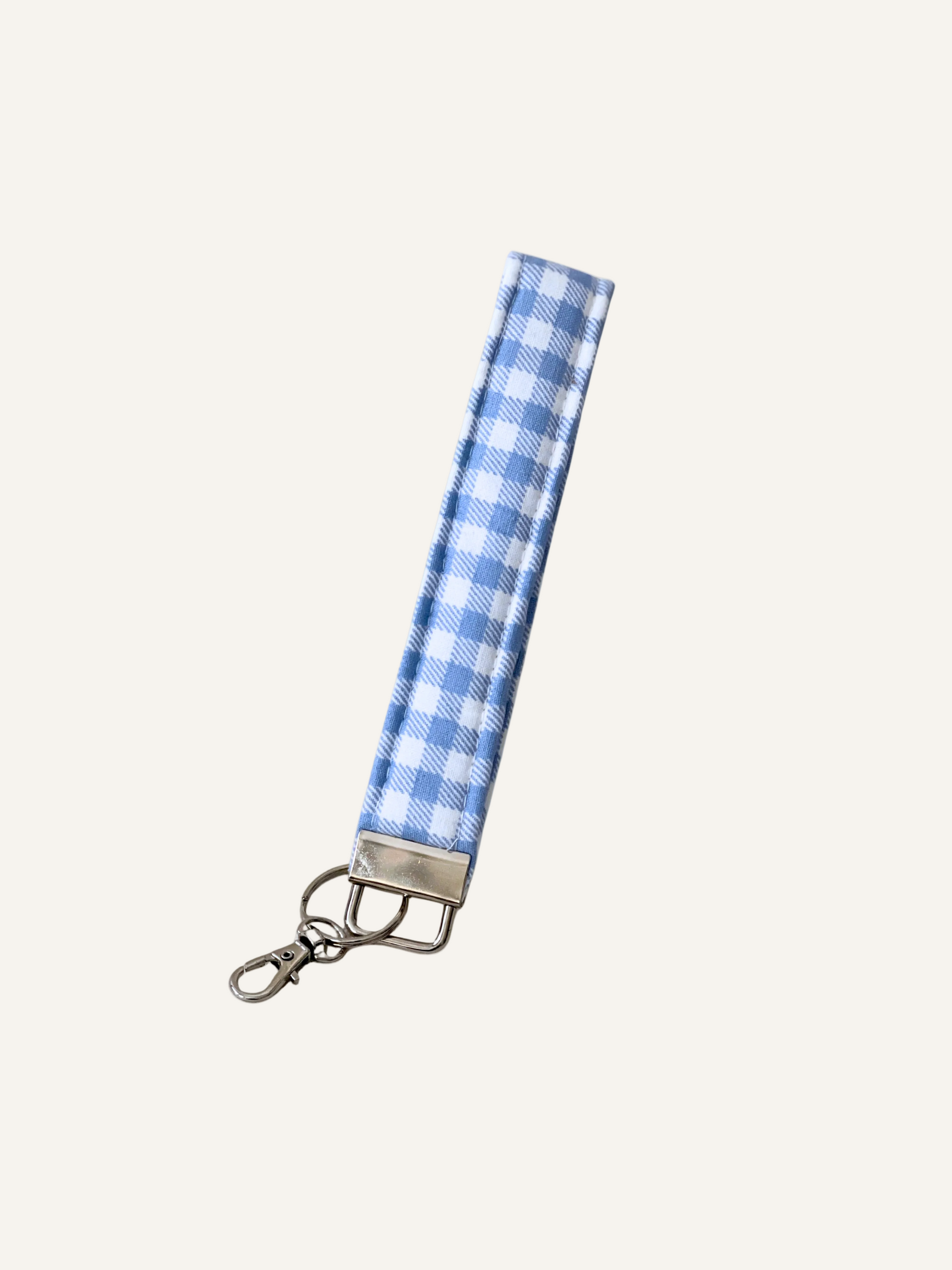 Blue and white checkered fabric keychain wristlet on a warm cream background