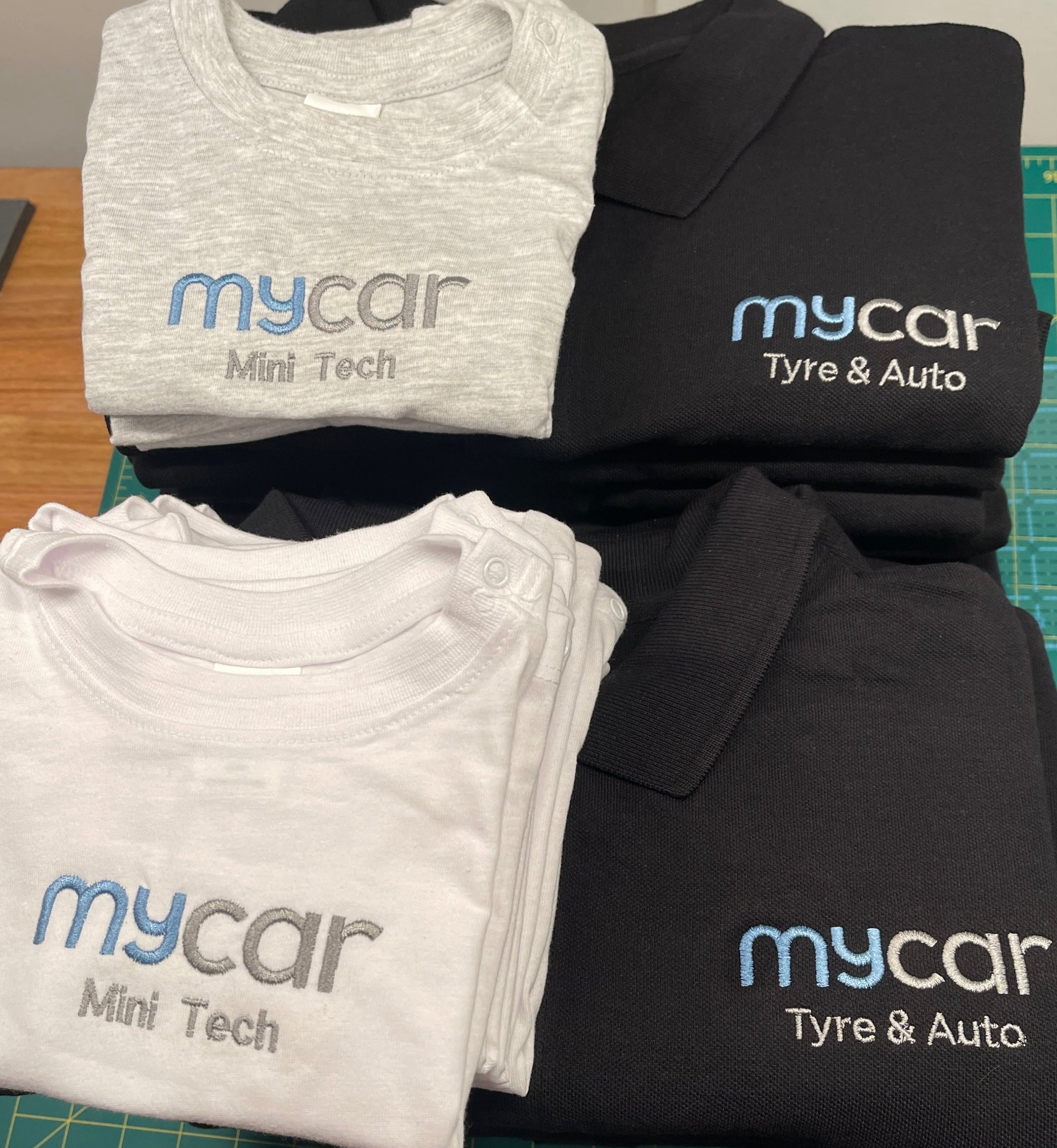 Folded shirts with 'mycar' branding on a cutting mat.