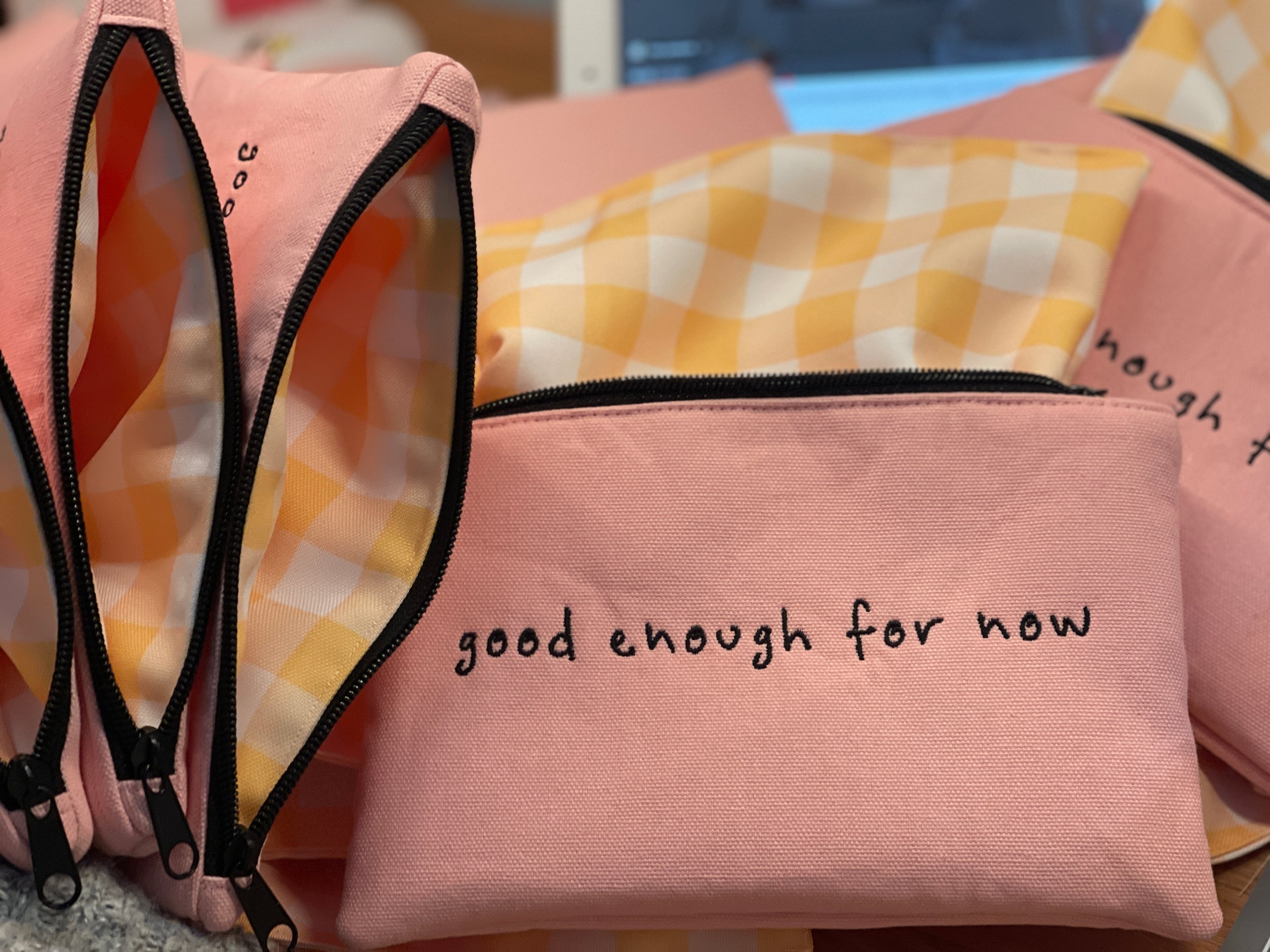 Pink pouch with 'good enough for now' text on a checkered fabric background