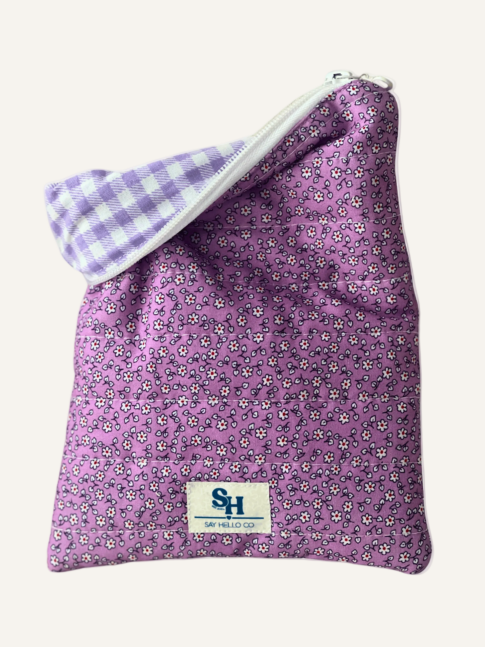 a quilted Kindle sleeve in purple floral with tiny white flowers with a purple and white gingham lining on a warm cream background