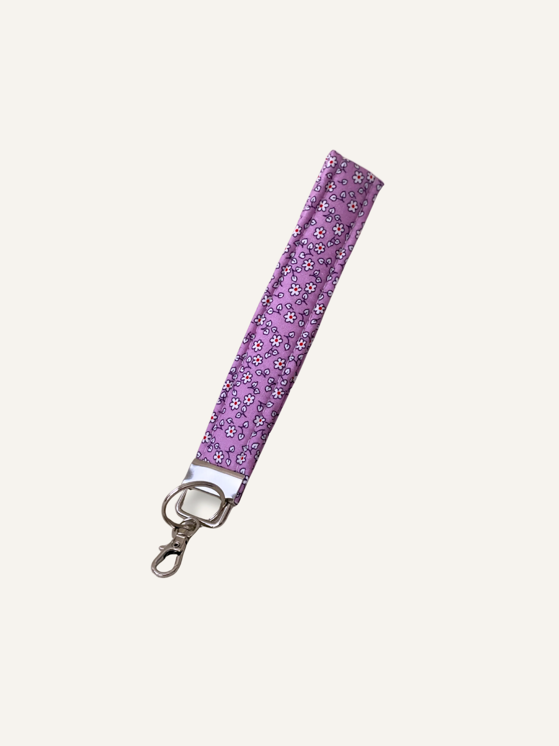 a padded fabric keyring wristlet in purple with tiny white flowers on a warm cream background