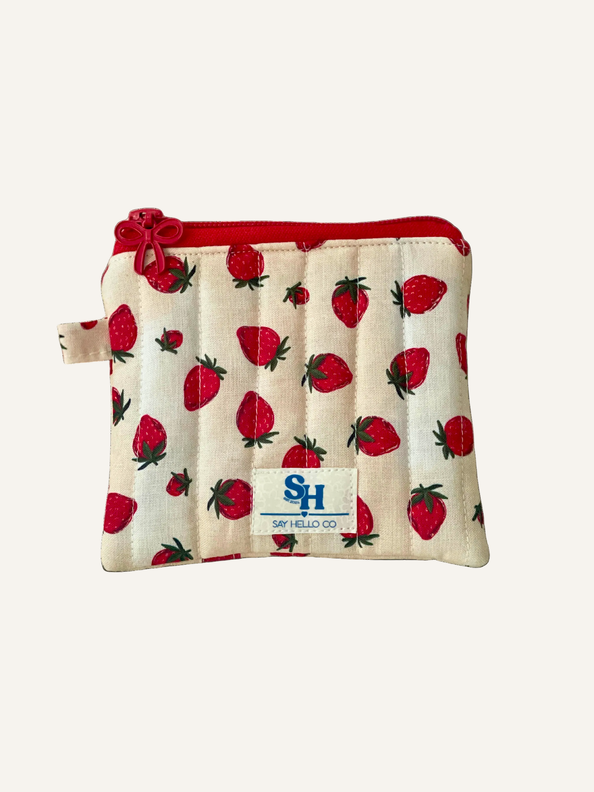 Small creamy beige pouch with strawberry pattern and red zipper on a cream background