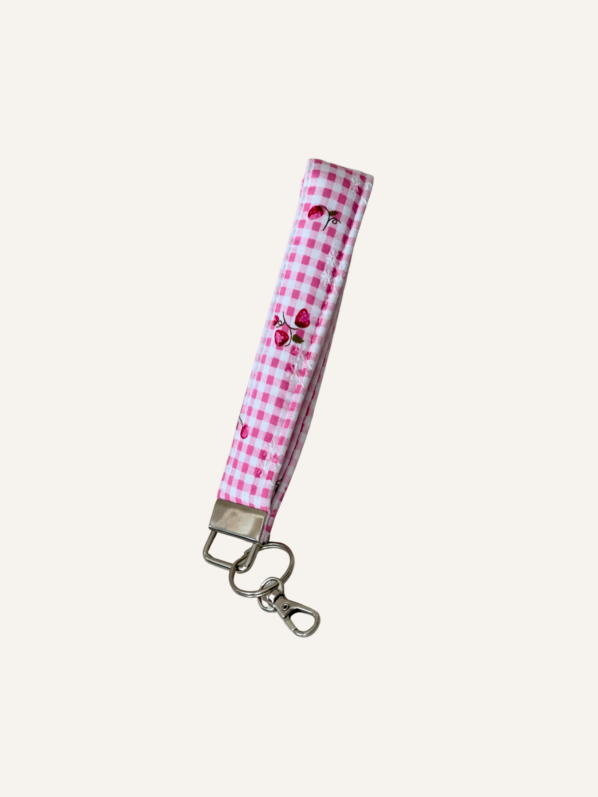 Pink gingham keychain with cherry and strawberry design on a warm cream background