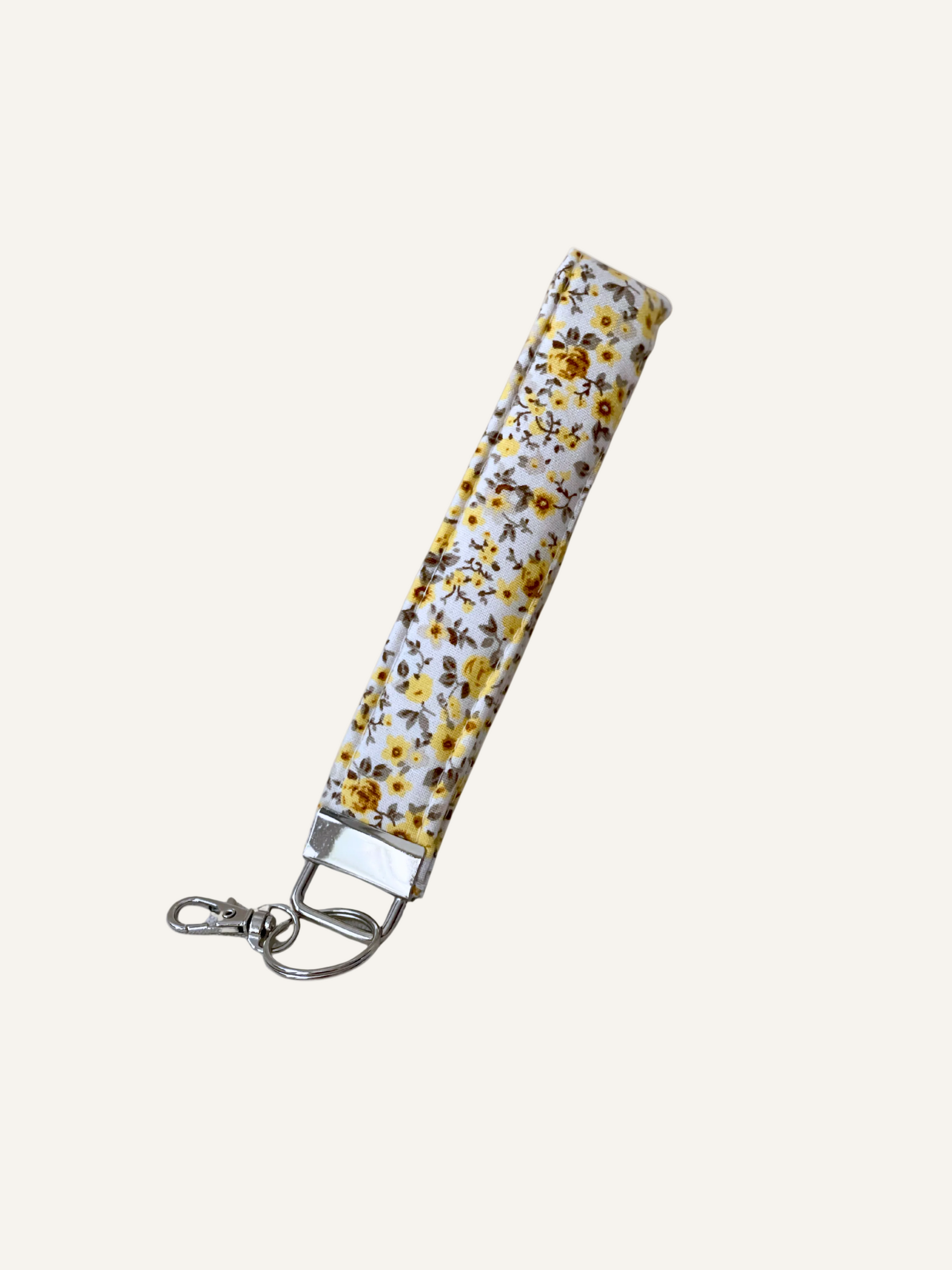 Yellow floral patterned keychain strap on a warm cream background
