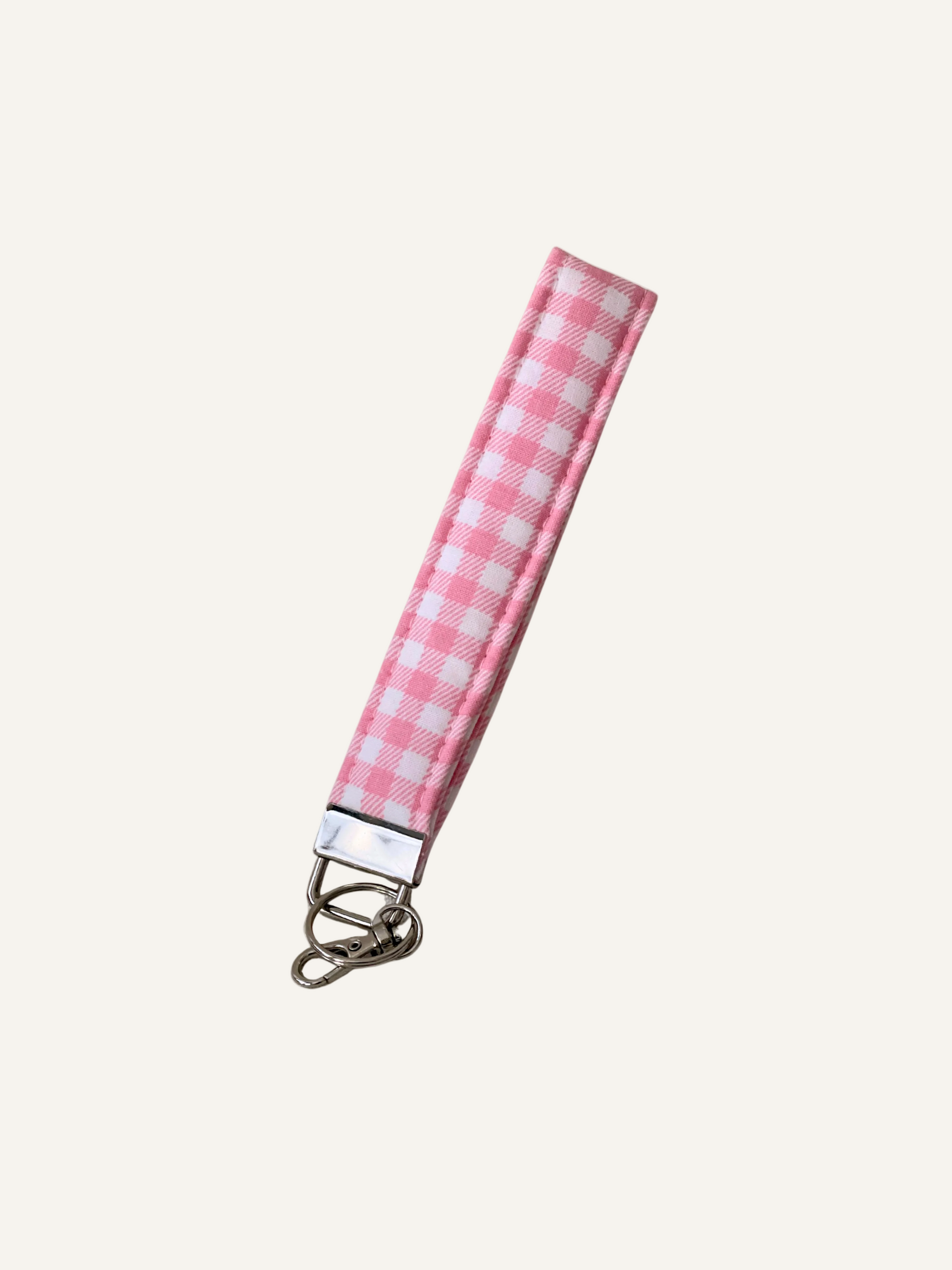 Pink and white checkered padded fabric keychain wristlet on a warm creambackground