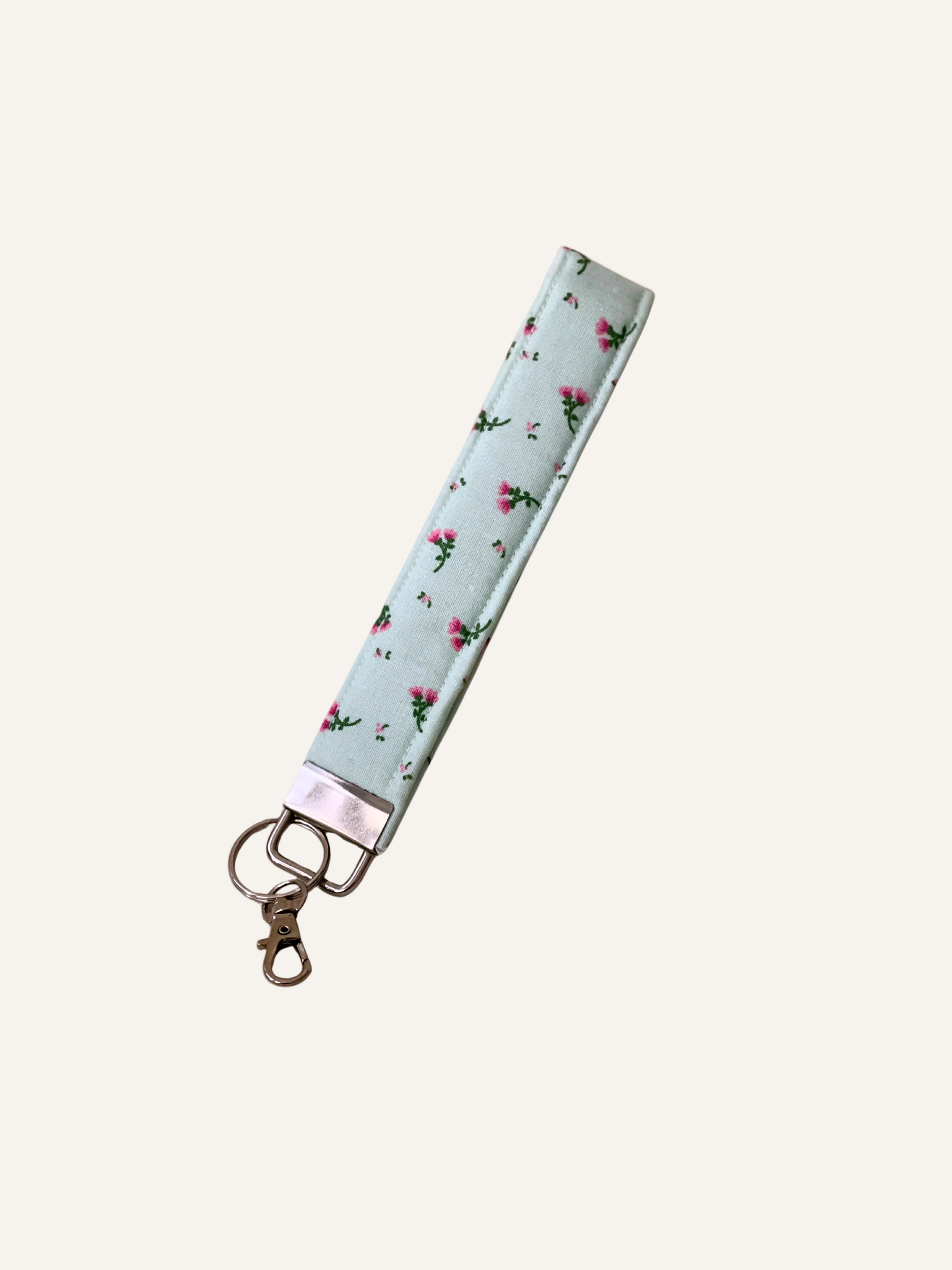 Green with pink Floral patterned keychain strap on a warm cream background