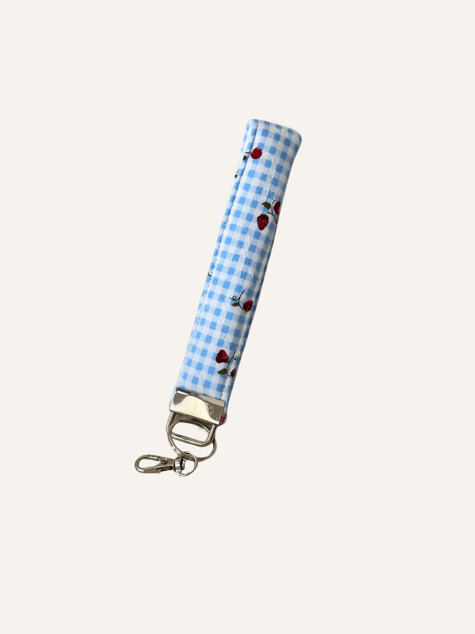 Blue checkered padded fabric keychain with cherry and strawberry pattern on a warm cream background