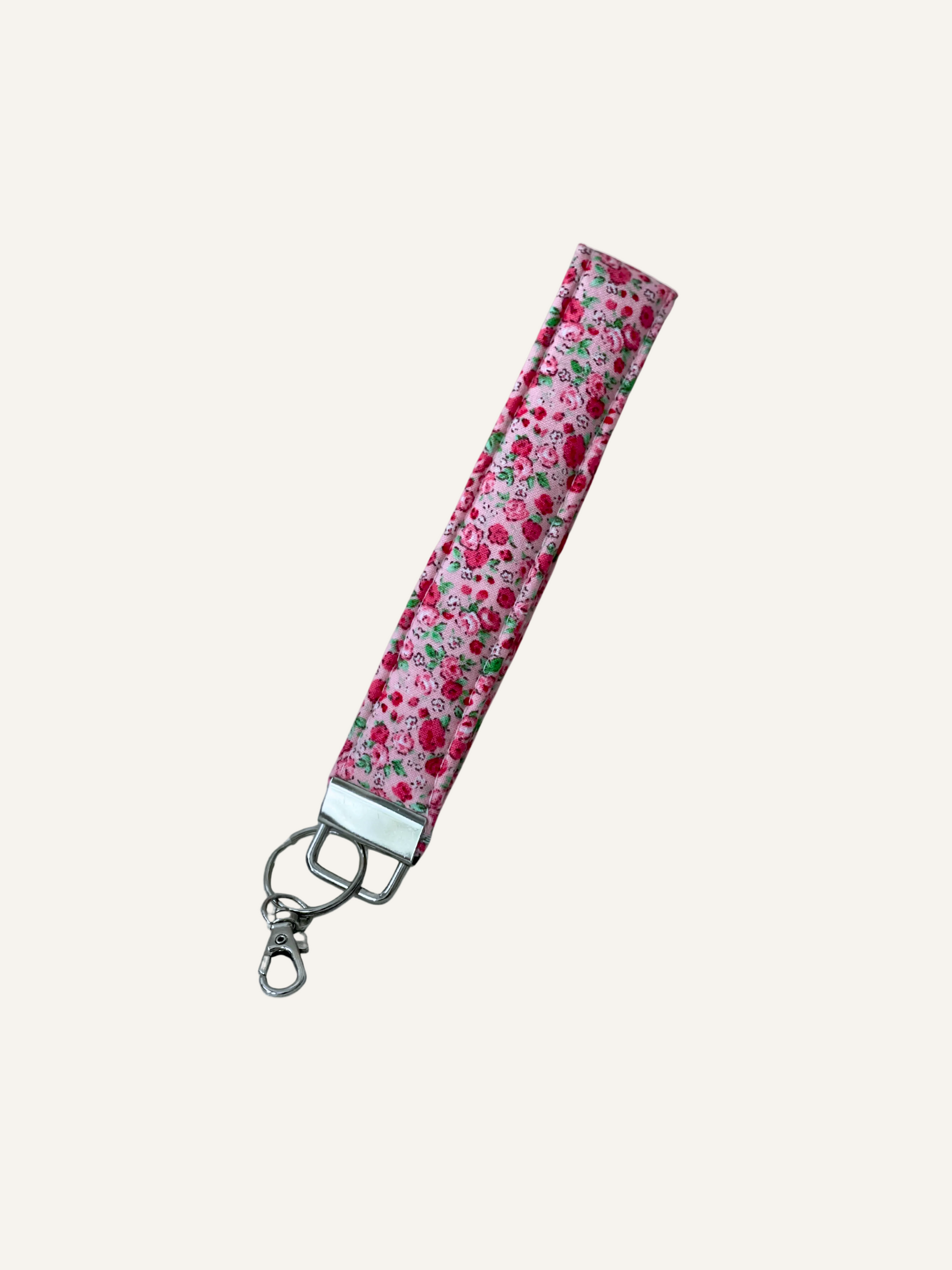 a padded fabric keyring wristlet in red and pink ditsy rose print on a warm cream background