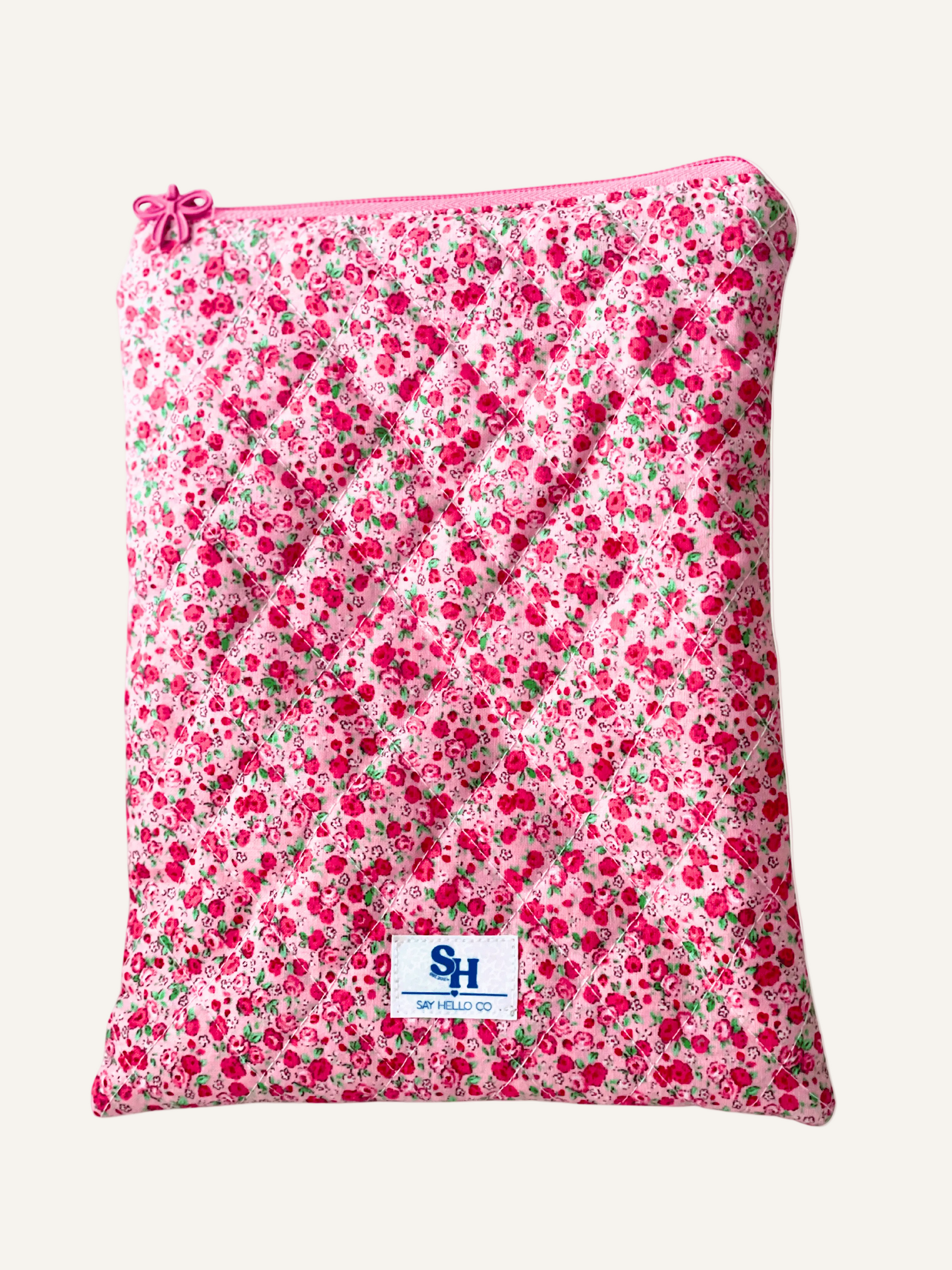 quilted book sleeve in a red and pink ditsy rose print. visible brand label on a white background