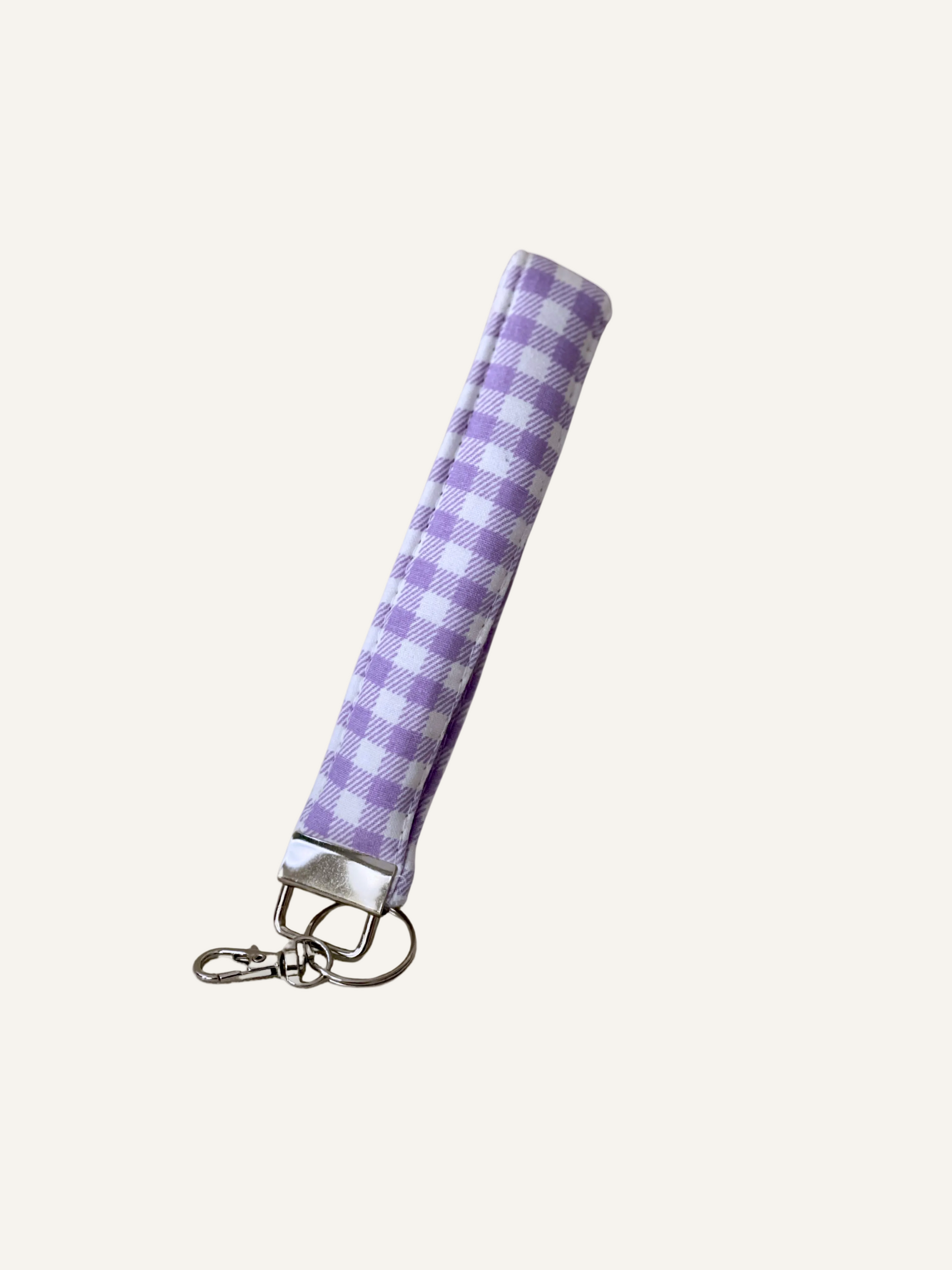 Purple and white checkered padded fabric keychain wristlet on a warm cream background
