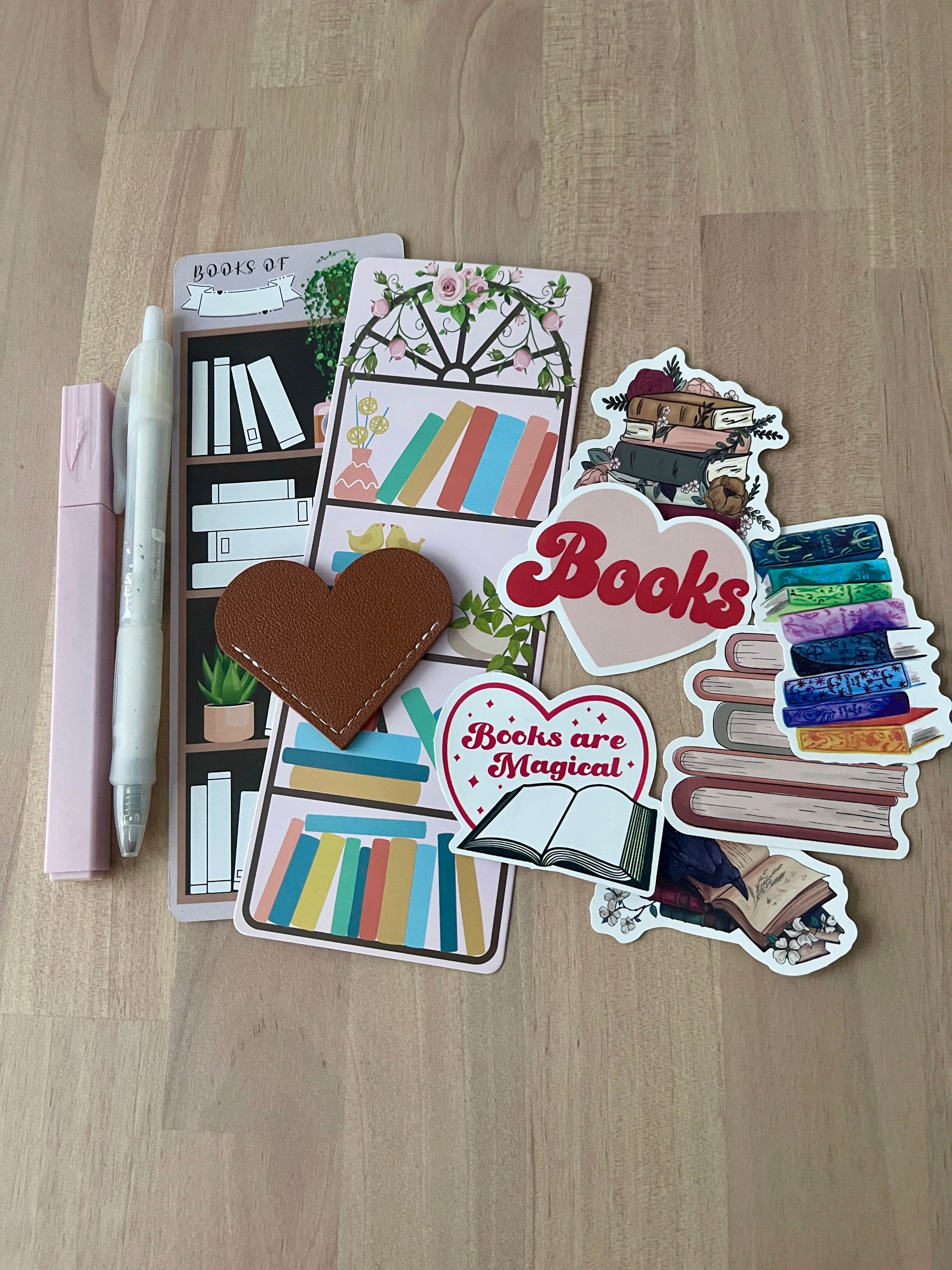 Collection of book-themed stickers, bookmarks, a highlighter and a pen on a wooden surface